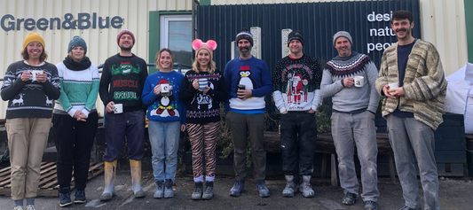 Green&Blue team stand outside the workshop in Christmas jumpers smiling at the camera