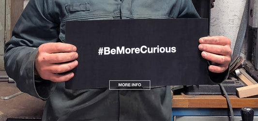 be more curious sign held in hands