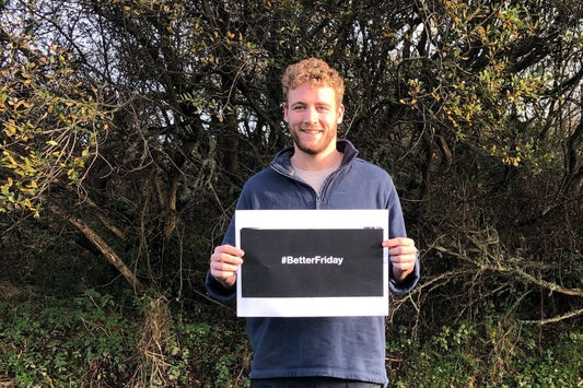 Elliot from Green&Blue stands in front of Nansmellyn Nature reserve holding a sign that says #BetterFriday